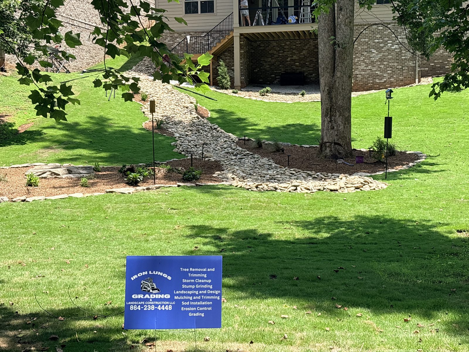 Dry creek bed and native plantings installed by Iron Lungs Grading in a Greenville, SC backyard to move runoff away from the foundation