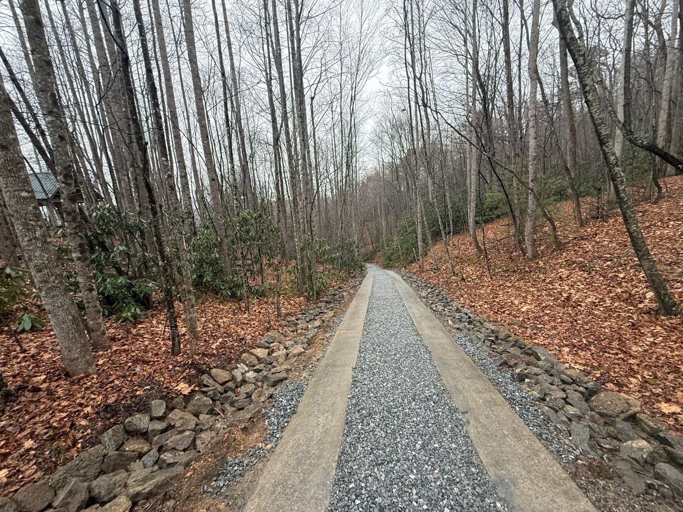Mountain gravel driveway winding through trees — restored after Hurricane Helene Hendersonville NC