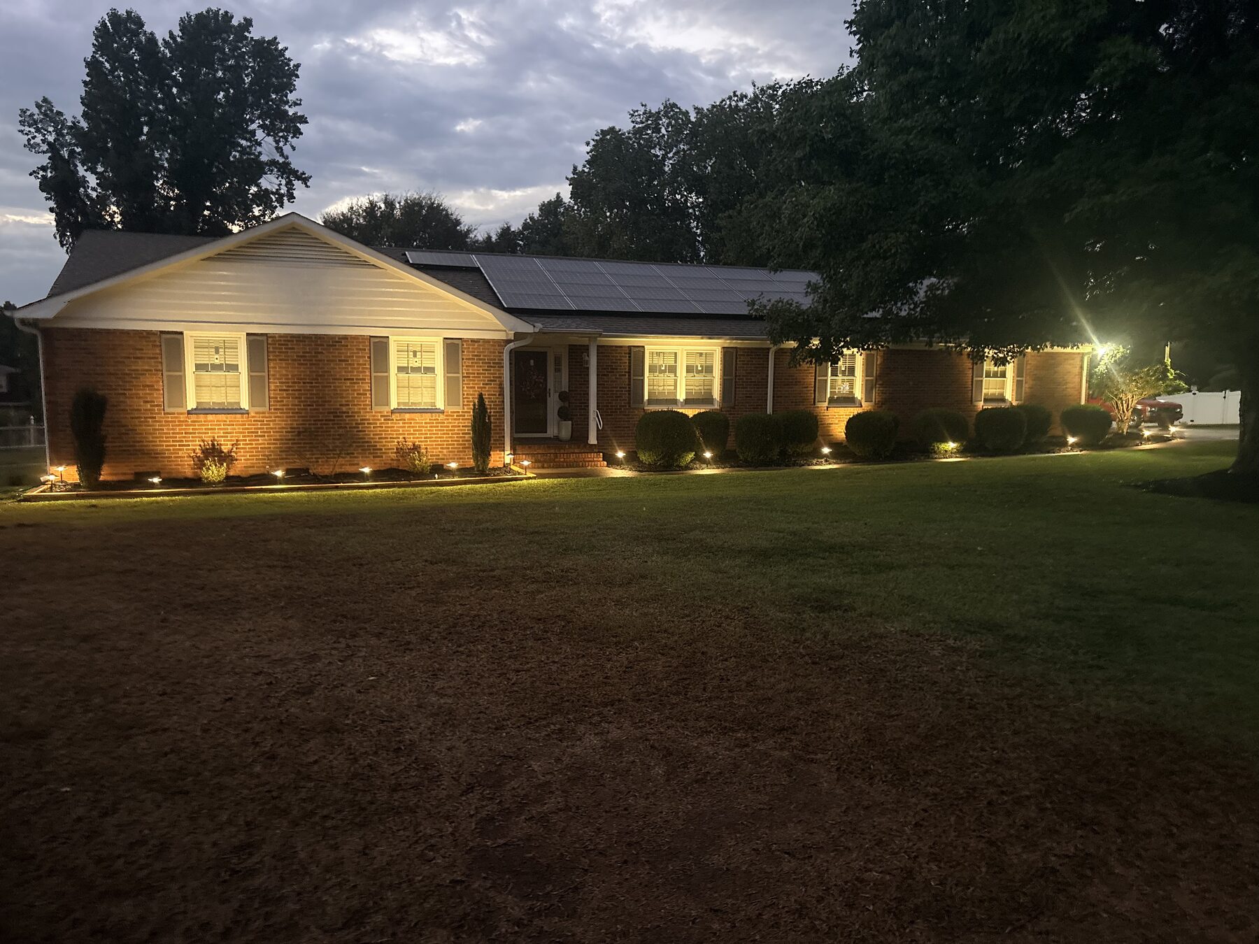Low-voltage LED path lighting washing the front of a brick ranch home at dusk in Greenville SC — Iron Lungs landscape lighting